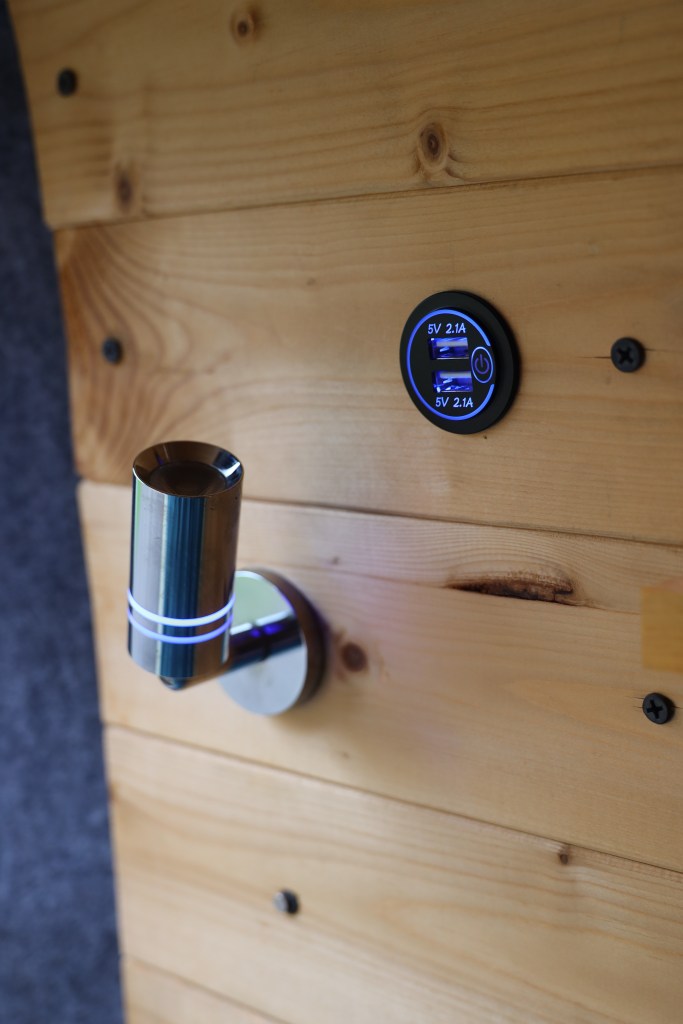 A modern USB charging station mounted on a wooden wall with a stylish metallic fixture.